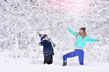 Fototapeta na wymiar Mom and son throw snow up in a snowy winter park. Joy of life concept.