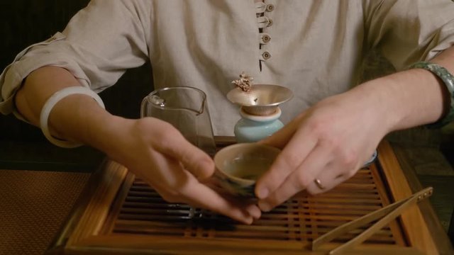 Gun Fu Cha. Tea Ceremony. Front view close up man drink chinese green oolong tea
