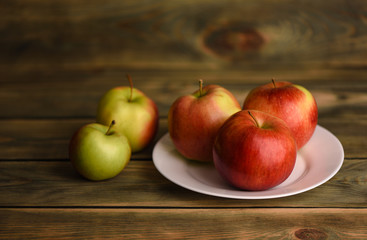 Apples on a white plate on wooden background