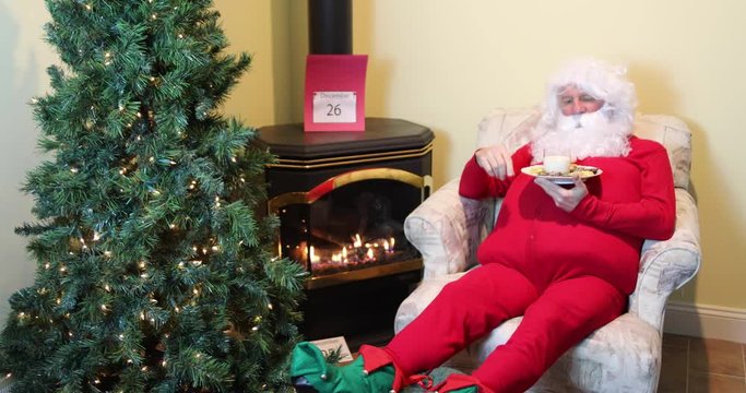 Santa Claus sick of eating  cookies and milk in house wearing red long johns relaxing the day after Christmas.