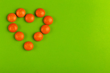 Coated glaze chocolate little orange candies shaped into heart