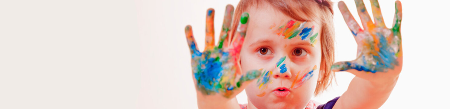Art, creative and happiness childhood concept. Portrait of colorful painted hands and face in a beautiful little child girl.