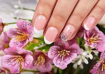 Obraz na płótnie Canvas Hand with artificial french manicured nails and pink flowers