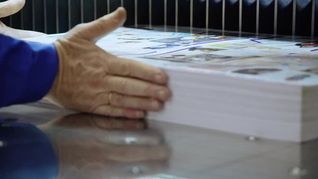 unrecognizable worker printing house. close up male hand dubs a stack of newspapers