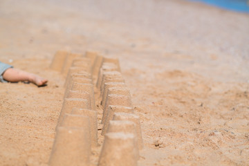 Fototapeta na wymiar Row of little sand castles on a sandy beach