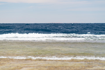 Waves breaking on a sandy beach in summer