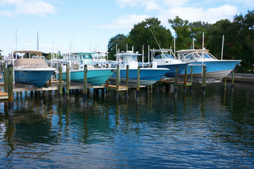 Expensive center console fishing boats on boat lifts at a marina dock