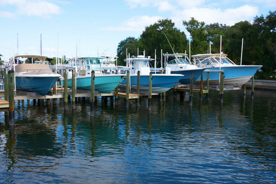 Expensive center console fishing boats on boat lifts at a marina dock