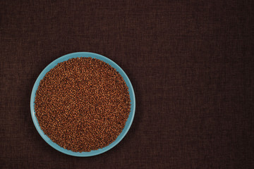 Buckwheat groats in a blue bowl and brown linen background