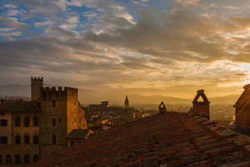 View of Arezzo historic center sunset skyline with old medieval towers and churches wrapped in mist