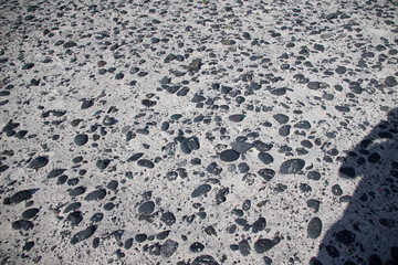 Schwarze Steine auf grauem Sandstrand