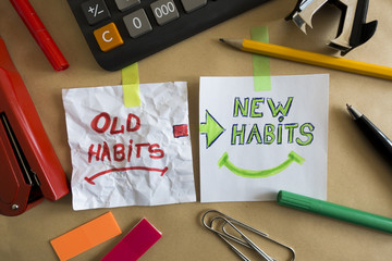 Old habits and new habits handwritten on white pieces of paper at the office