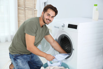 Young man using washing machine at home. Laundry day