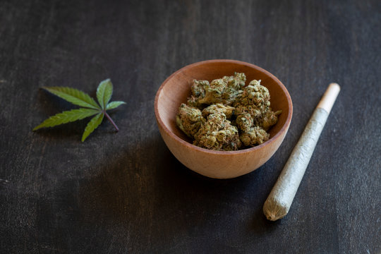 Wooden bowl of marijuana and a rolled joint