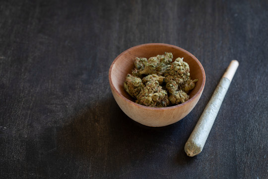 Wooden bowl of marijuana and a rolled joint