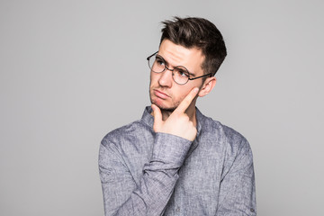 Handsome young man in eyesglasses standing and looking up isolated on the gray background