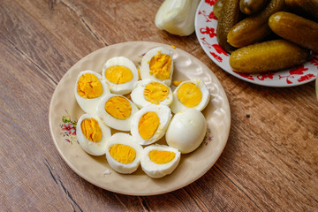 Hard boiled chicken eggs in a porcelain plate on vintage wooden table