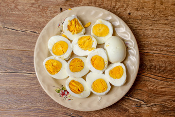 Hard boiled chicken eggs in a porcelain plate on vintage wooden table