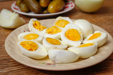 Hard boiled chicken eggs in a porcelain plate on vintage wooden table