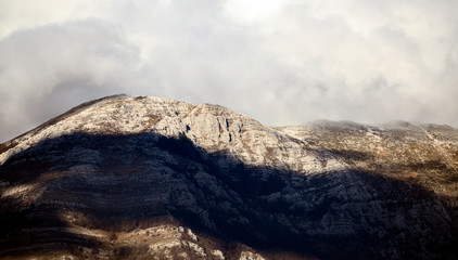 Beautiful view of some snowy mountains surrounded by soft clouds during sunset, Italy.