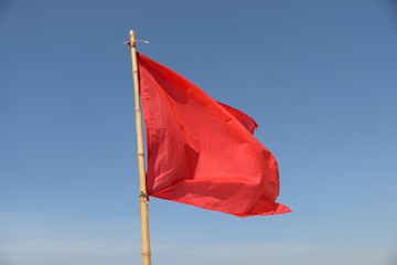 red flag swaying in the wind on a blue sky background