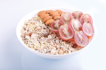 A plate with muesli, almonds, pink grapes isolated on a white background.