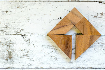 Tangram puzzle in arrow in square shape on old white wood background