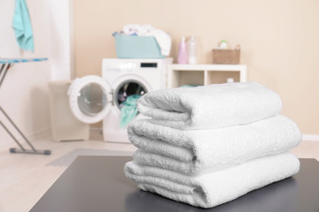 Stack of clean towels on table in laundry room. Space for text