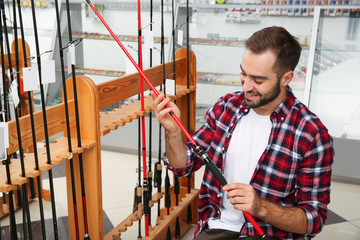 Man choosing fishing rod in sports shop