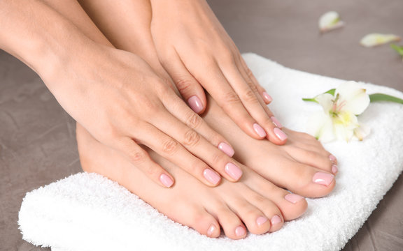 Woman touching her smooth feet and towel on grey background, closeup. Spa treatment