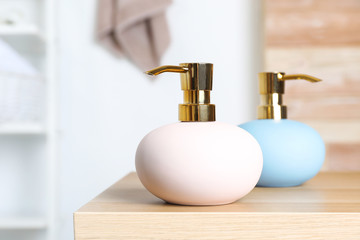 Obraz premium Stylish soap dispensers on table against blurred background. Space for text