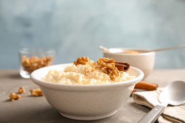 Creamy rice pudding with cinnamon and walnuts in bowl served on table. Space for text