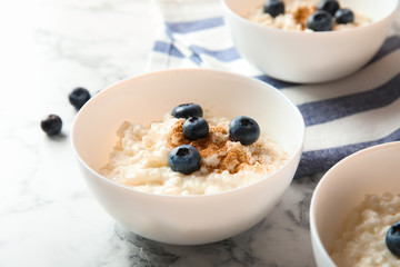 Creamy rice pudding with cinnamon and blueberries in bowls on marble table