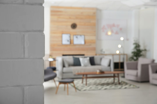 White brick wall and blurred living room interior on background