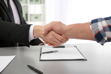Lawyer shaking hands with client in office, closeup