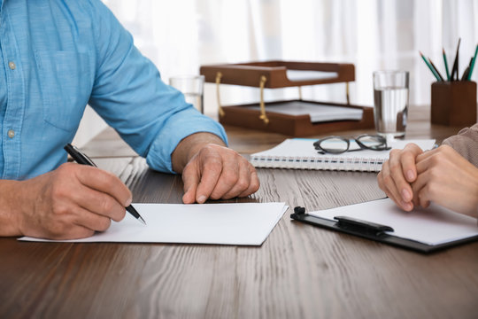 Senior man signing document in lawyer's office