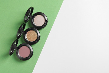 Flat lay composition with different eye shadows on color background. Space for text