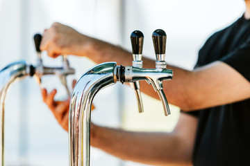 Close-up of beer tap with man serving as background