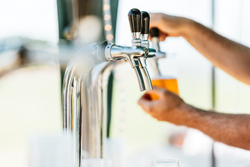 Close-up of beer tap with man serving as background