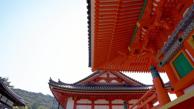 japanese style building exterior in red white green wooden. amazing design of shinto under sunny day blue sky in summer with mountain in background. 1200 years old Buddhist temple of Kiyomizu dera.