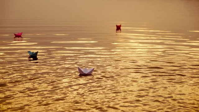 Floating paper boats on the water at sunset. Paper boat. Origami.