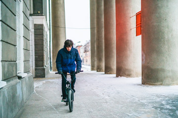 young male ride black bmx in winter cloudy day under roof between columns b