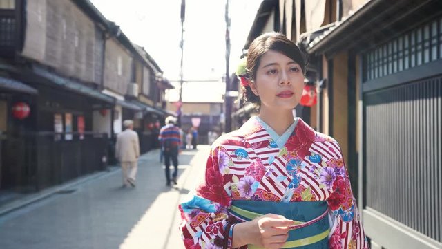 fast motion woman in kimono costume in kiyomizu zaka street on Asia travel. Asian lady looking around outside store. red lanterns hanging on the roof in traditional japanese wooden house. 