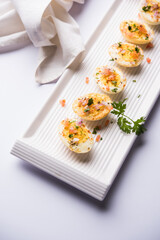 Fried hot boiled egg masala is a popular healthy breakfast or starter menu from India. With onion, coriander, black pepper, tomato and salt sprinkled over half of eggs