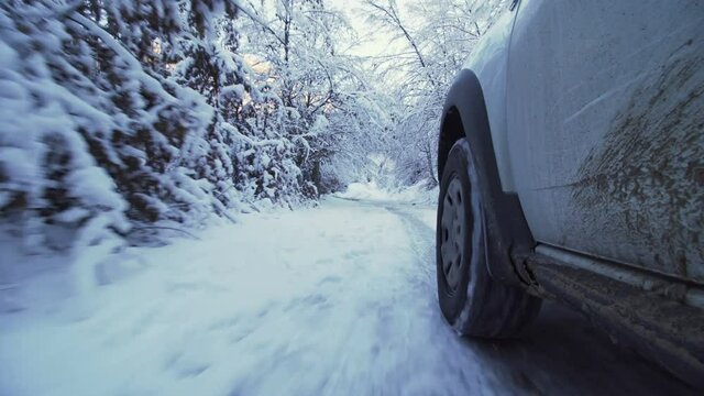 dirty white suv driving on a frozen road in the mountains with frozen trees above