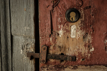 Old lock and latch on distressed old wooden door.