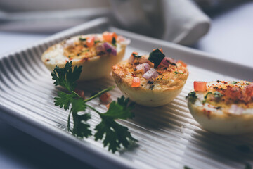 Fried hot boiled egg masala is a popular healthy breakfast or starter menu from India. With onion, coriander, black pepper, tomato and salt sprinkled over half of eggs
