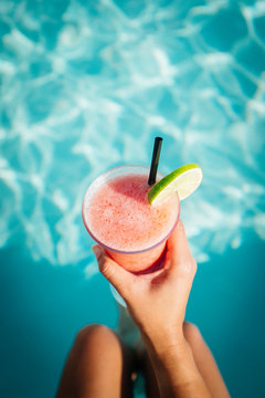 A woman holds a frozen margarita near a pool on vacation
