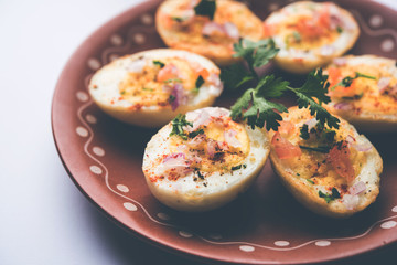 Fried hot boiled egg masala is a popular healthy breakfast or starter menu from India. With onion, coriander, black pepper, tomato and salt sprinkled over half of eggs