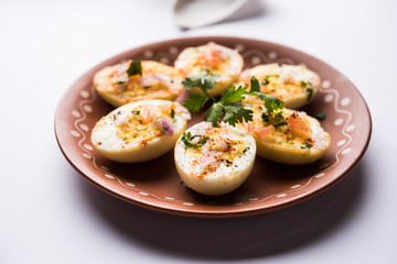 Fried hot boiled egg masala is a popular healthy breakfast or starter menu from India. With onion, coriander, black pepper, tomato and salt sprinkled over half of eggs